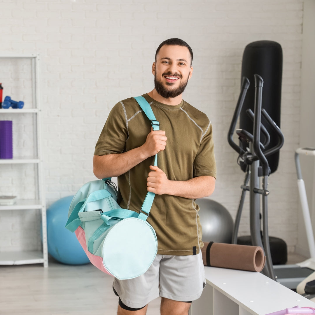 Man holding a colorful exercise bag in a home gym setting