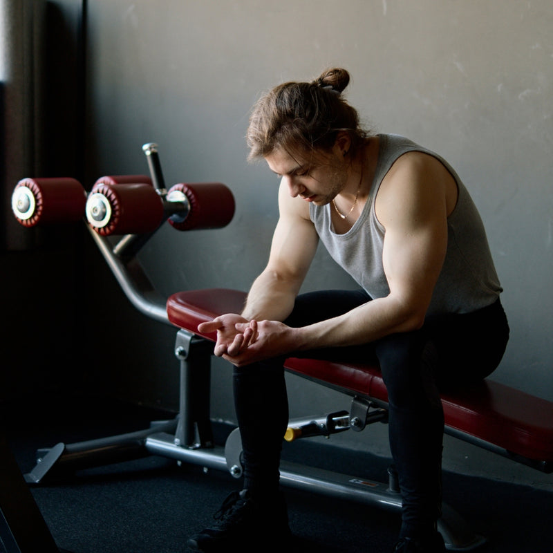 Man sitting on a weight bench in a gym setting