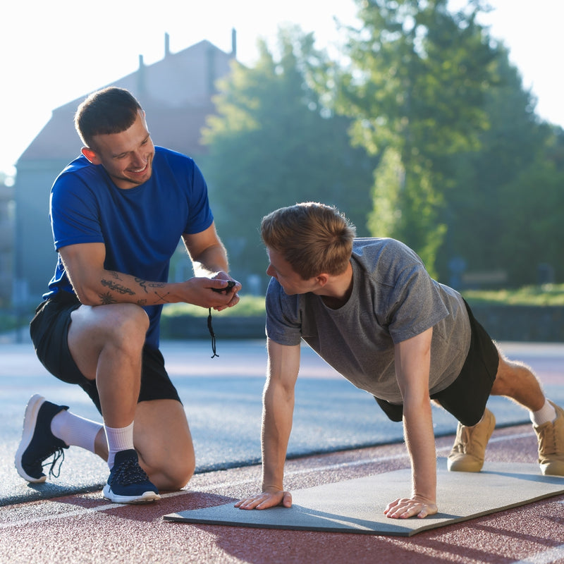 Two men exercising outdoors on a track with trees in the background