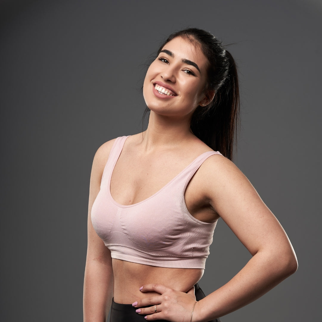 Woman wearing a pink sports bra against a gray background